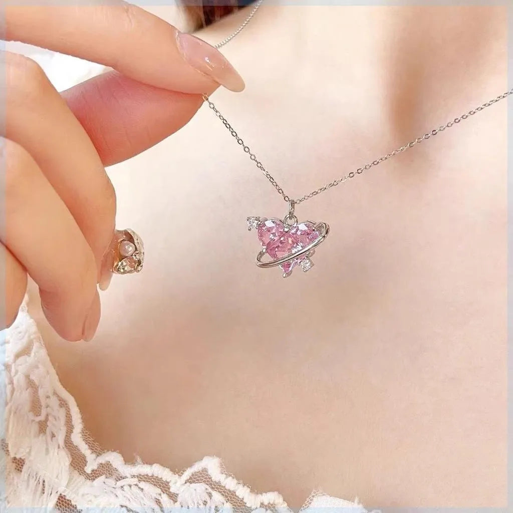 Pink heart-shaped necklace being worn with a blurred background