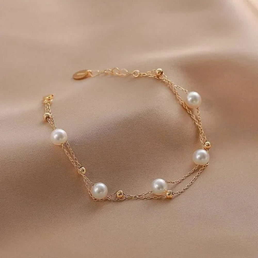 Gold bracelet with pearls on a beige fabric background