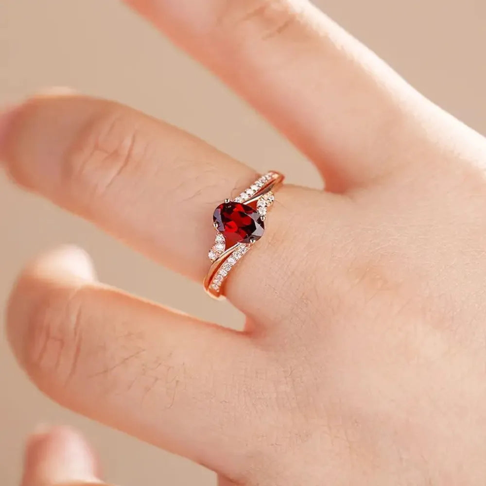 Ring with a red gemstone on a finger against a neutral background
