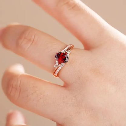 Ring with a red gemstone on a finger against a neutral background