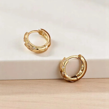 Gold hoop earrings with embedded stones on a light background