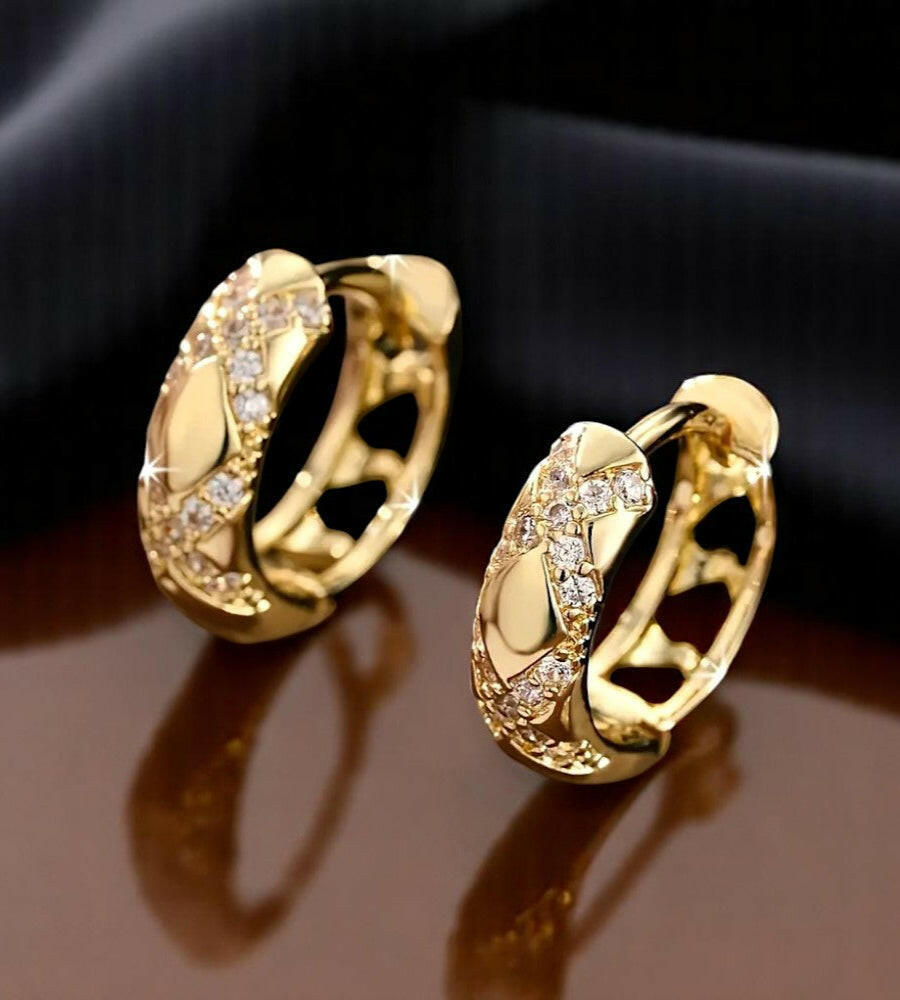 Gold hoop earrings with diamond accents on a dark background
