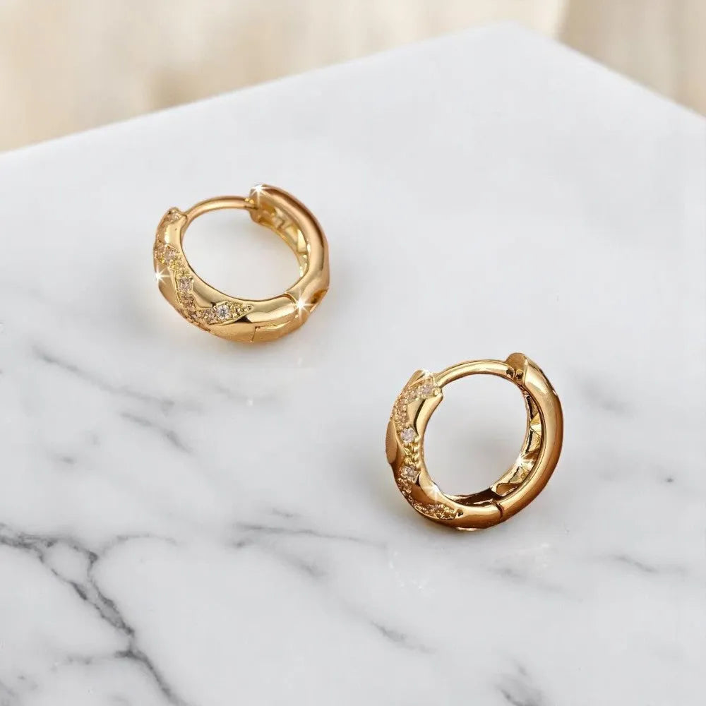 Gold hoop earrings on a marble surface