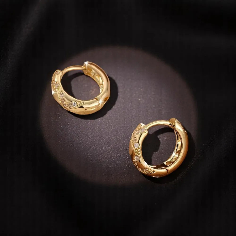 Pair of gold hoop earrings on a dark background