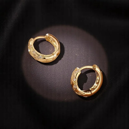 Pair of gold hoop earrings on a dark background