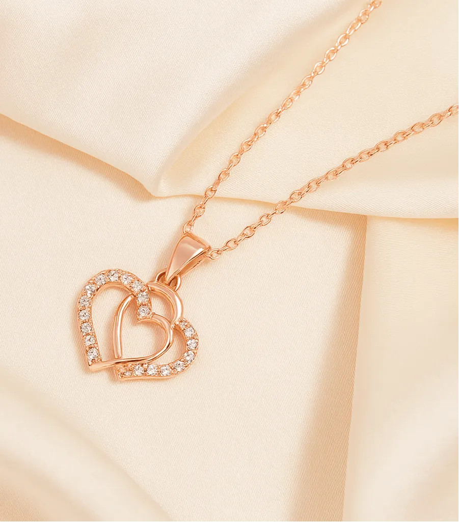 Rose gold necklace with a heart-shaped pendant on a beige background