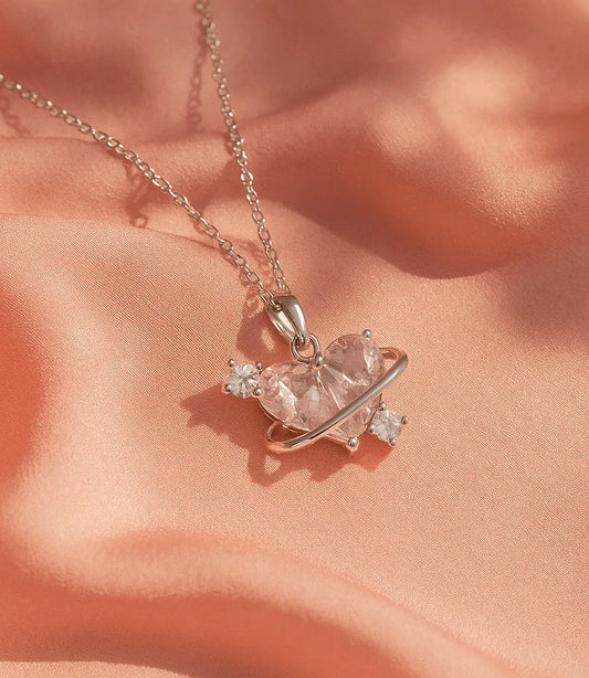 Necklace with a heart-shaped pink gemstone pendant on a soft peach fabric background
