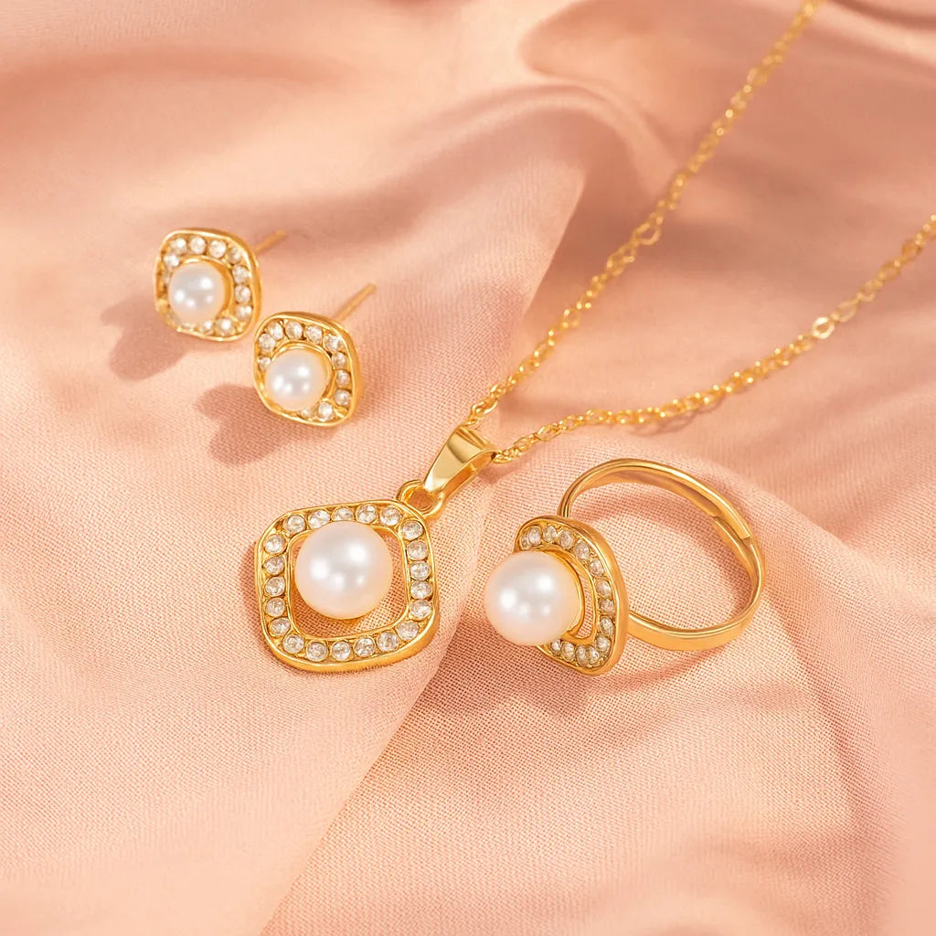 Gold jewelry set with pearls on a soft pink fabric background