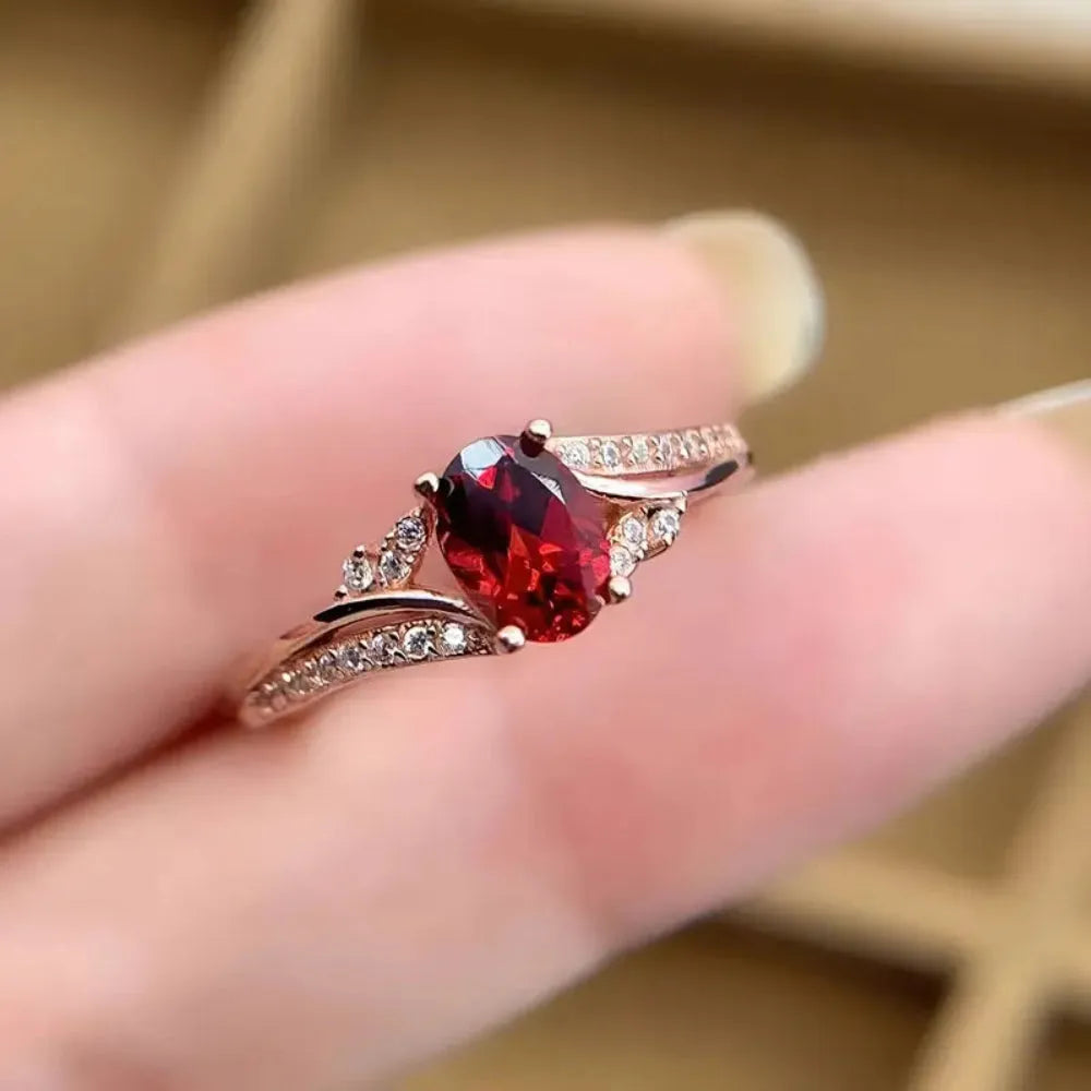 Ring with a red gemstone on a finger against a blurred background