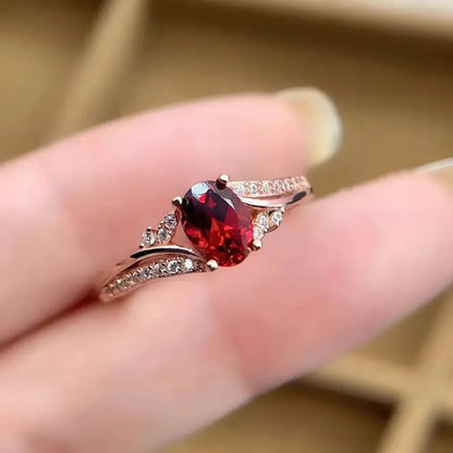 Ring with a red gemstone on a finger against a blurred background