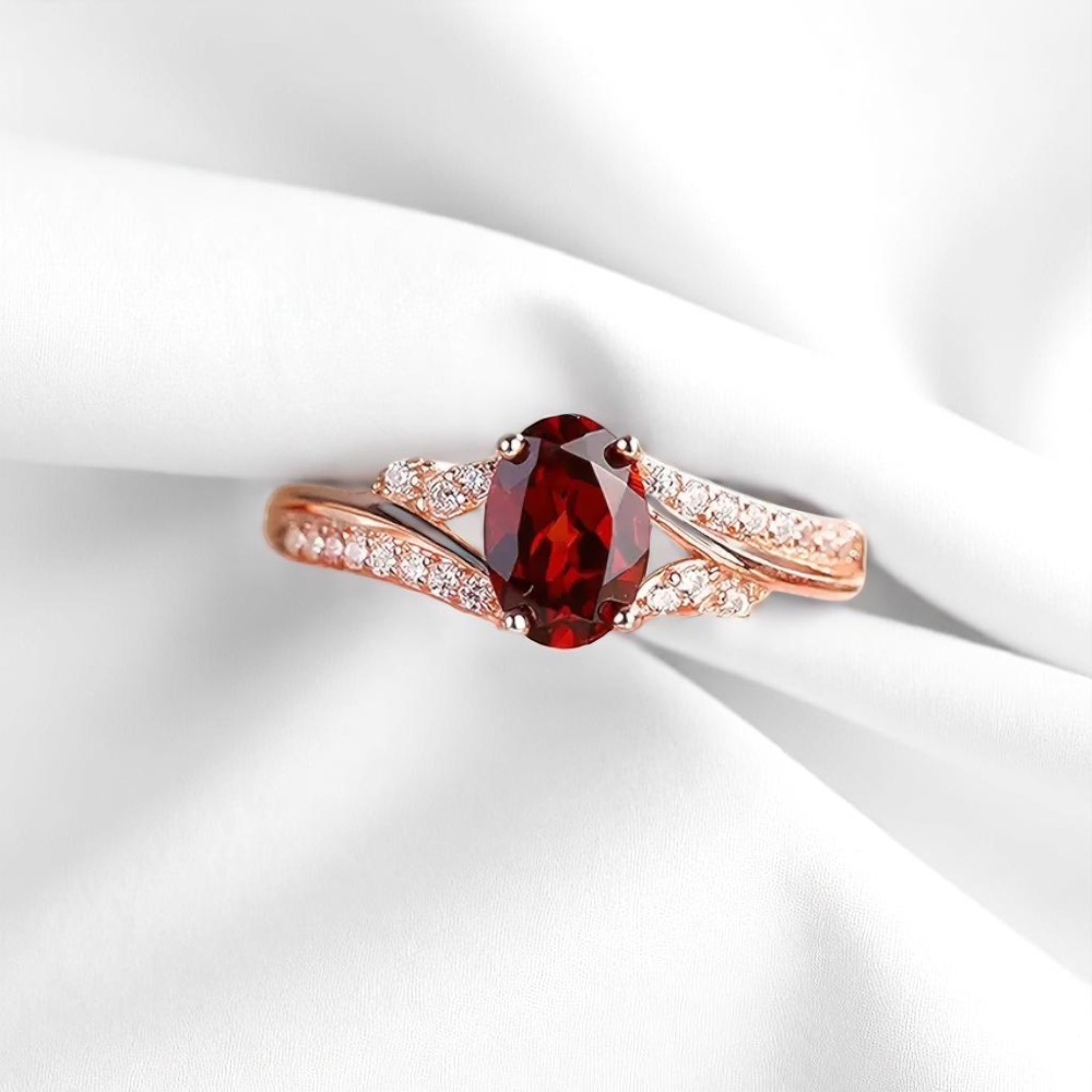 Rose gold ring with a red gemstone on a white fabric background