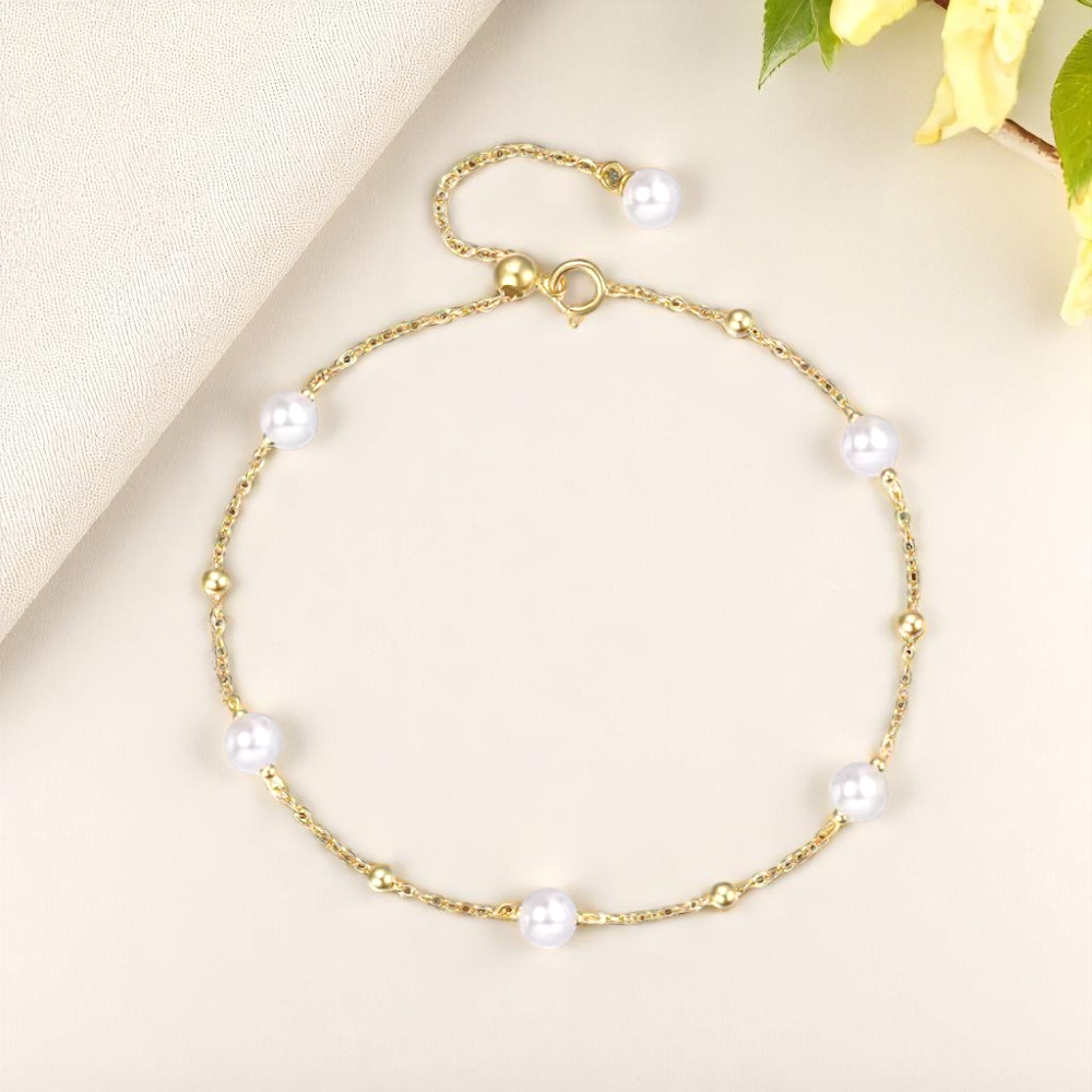 Gold bracelet with pearls on a light beige background