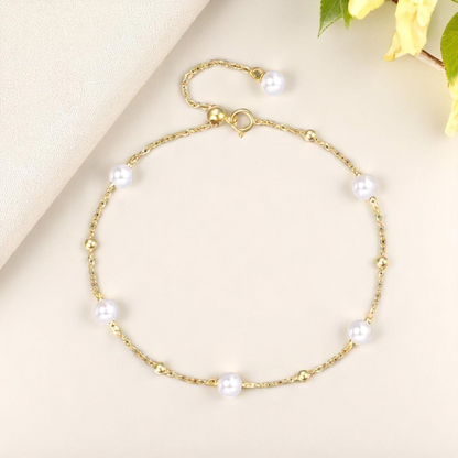 Gold bracelet with pearls on a light beige background