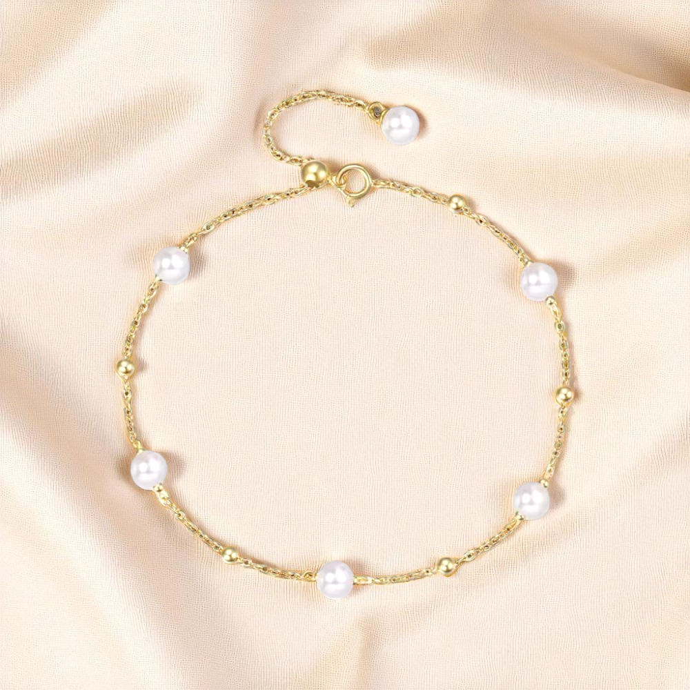 Gold bracelet with pearls on a light beige background